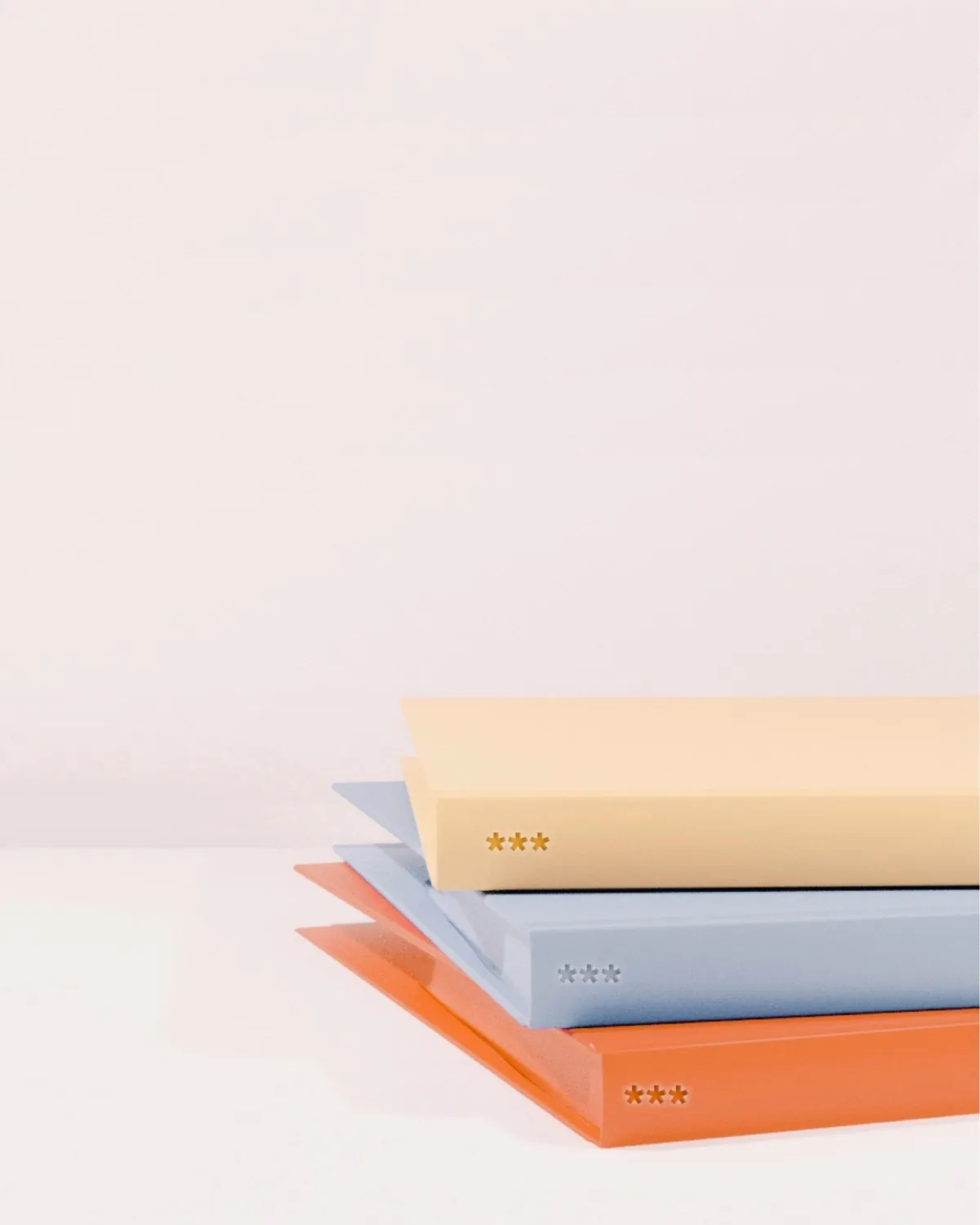 Stacked cream, blue, and orange notebooks
